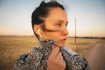 A young woman looking in a distance walking in a countryside path. Brunette girl is listening to...