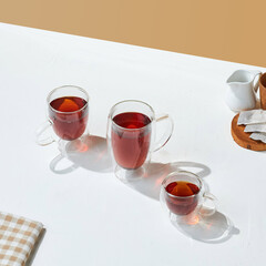 a variety size of transparent double wall glass with tea inside it, on a white and beige colored background.