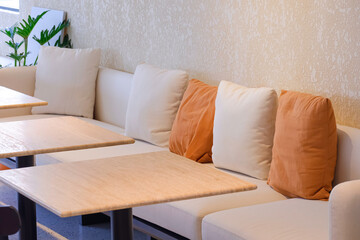 Selective focus at row of cushions on couch with wooden desks in beige tone style inside of modern...