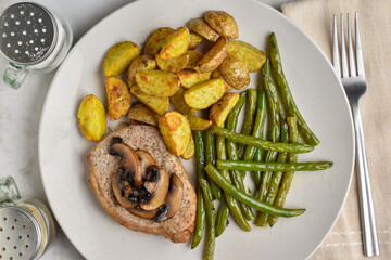 bone less pork chop top with mushrooms and a side  of green beans