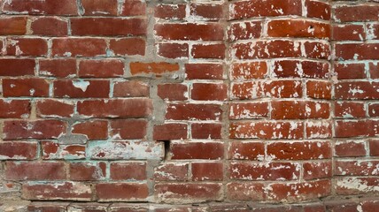 fragment of a brick wall with a semicircular protrusion made of red bricks with smudges of white paint, part of the facade of an old brick building as a red brick background texture