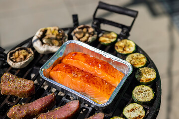 veal meat, salmon and zucchini on garden grill with charcoal