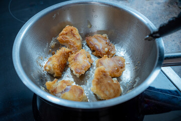 Baked pork pieces in a steel pot on the ceramic hob