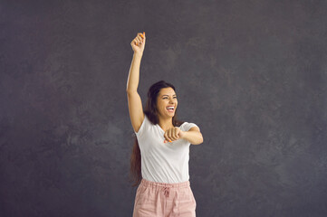 Happiness. Beautiful young happy woman in good mood dances, jumps and has fun on studio gray...