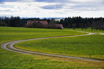 typical country view on a grey autumn day with farmhouse, lane, trees and mountains in the background