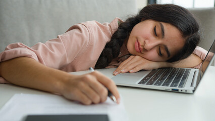 Tired sleeping woman sleep closed eyes on office table sleepy overworked female student girl exhausted weary lazy Indian Arabian businesswoman fall asleep napping doze with laptop work online learning