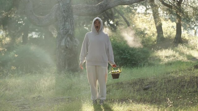 Cool and Sunny Morning in the Forest, a Young Woman with a Basket in her Hands, Illuminated by Beams, Yawns, and Vapor Escapes from her Mouth.