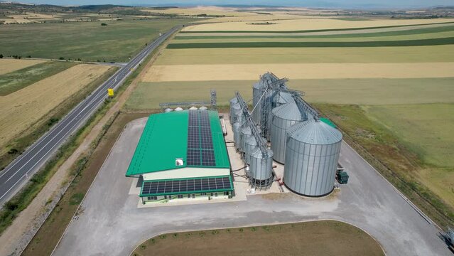 Silver silos storage tanks in corn field, aerial shot