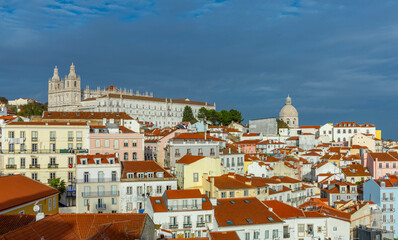 Fototapeta na wymiar Lisbon, Portugal. 8 December 2023. Panoramic view of the beautiful skyline of Lisbon, Portugal, with orange roofed, colorful houses in the Alfama district during a sunny and cloudy day.