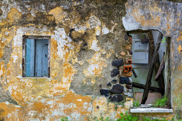 Lisbon, Portugal. 6 December 2023. Ancient building closeup of surface brick wall concrete plaster of an abandoned house with broken windows black stone grey cement and ocher and white paster.