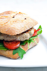 homemade turkey burger with cherry tomatoes and arugula in ciabatta