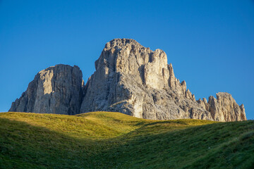 Sun shines on mountain in the dolomites: Grohmannspitze in Langkofelgruppe in the morning with...