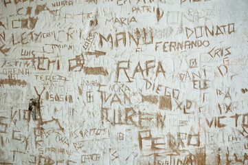 Grafiti con nombres de niños escritos en una pared de un pueblo en España.