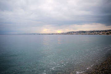 Fototapeta premium The rays of the setting sun break through the clouds over the Mediterranean Sea in Nice
