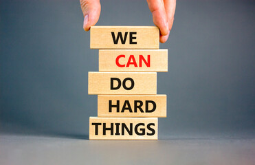 We can do hard things symbol. Concept words We can do hard things on wooden blocks. Beautiful grey table grey background. Businessman hand. Business, we can do hard things concept. Copy space.