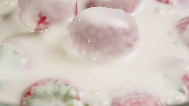 Pouring milk on fresh red strawberries in bowl close-up. Adding yogurt in sweet berries .Health and food concept. Harvesting 