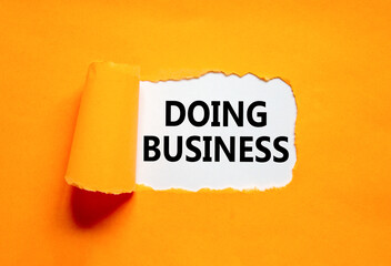 Doing business symbol. Concept words Doing business on beautiful white paper. Beautiful orange table orange background. Business, motivational Doing business concept. Copy space.