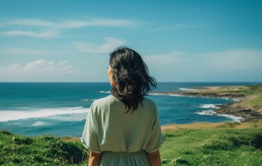 Fototapeta premium Back view of a woman in beautiful clothes standing on the beach 