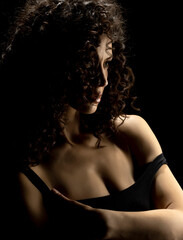 Sensual portrait of beautiful curly serious curly woman a black background