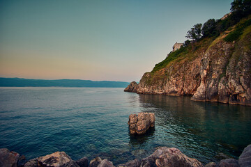 beautiful sunset over the sea with rocks and boat in the foreground