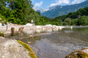 Woman with baby carrier with scenic view of Soca River, Bovec, Triglav National Park,Slovenia. Magnificent Soca Valley in Julian Alps. Wanderlust in untamed Slovenian Alps. Hiking in alpine wilderness - obrazy, fototapety, plakaty
