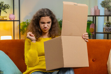 Angry dissatisfied shopper child girl unpacking parcel feeling upset and confused with wrong...
