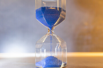 hourglass wiht blue sand on a black background, time