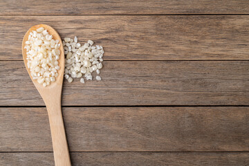 Dried canjica, hominy or white corn on a spoon over wooden table with copy space