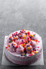 Pink Sponge cake decorated with small meringue on top on gray background