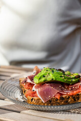 Toast with salmon, avocado and cheese. Breakfast at wooden table.?lose up. Restaurant, cafeteria, bar menu.