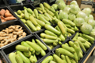 Shop window with zucchini, cabbage and ginger in plastic boxes