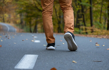 Autumn Stroll: Close-Up of Young Man's Legs Walking on the Road