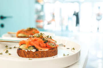 Healthy breakfast. Avocado toasts with salmon and poached eggs on ceramic plate