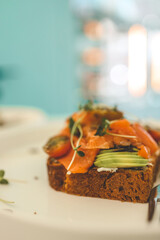 Healthy breakfast. Avocado toasts with salmon and poached eggs on ceramic plate