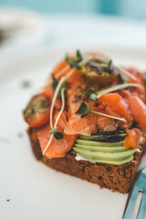 Healthy breakfast. Avocado toasts with salmon and poached eggs on ceramic plate