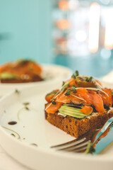 Healthy breakfast. Avocado toasts with salmon and poached eggs on ceramic plate