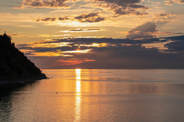 Romantic sunset painting the horizon from charming coastal village of Fiesa, Slovenia, Europe. Scenic view of coastline Gulf of Piran. Tranquil waters of the Adriatic Sea reflecting vibrant sun beams © Chris