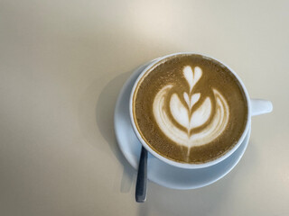 Cappuccino with heart-shaped foam on a brown background. Top view with free copy space for text. Art's Latte in a cup.