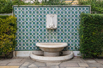 Fountain decorated with modern industrial type tiles located in Santa Luzia belvedere, in Lisbon, Portugal - obrazy, fototapety, plakaty