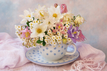 A bouquet of spring flowers in a cup on the table, a beautiful still life, a postcard - 702985387