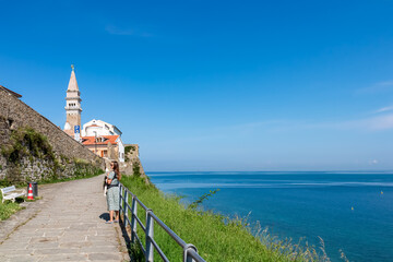 Woman with baby carrier on scenic walking path between Fiesa and coastal town of Piran, Slovenian...