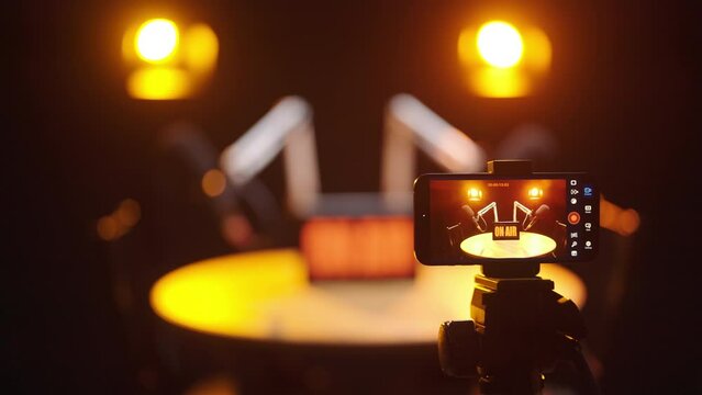 Smartphone camera recording podcast with spotlights in black studio 4K