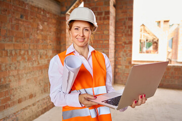 Joyous construction professional using laptop in uncompleted building