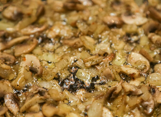 We cook mushrooms. Chopped mushrooms and golden onions in a frying pan close-up. Gastronomic background. Onions with mushrooms are fried in a frying pan. close-up, selective focus.