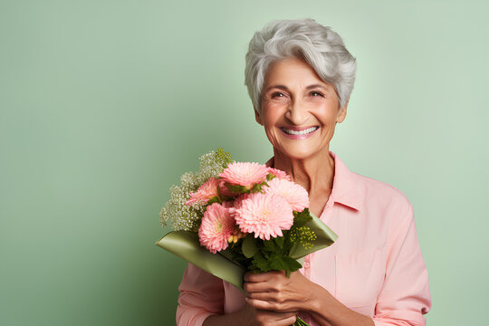 Senior person holding flowers, old woman smiling with pink bouquet on green background