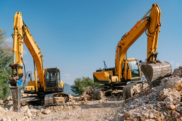 Two Yellow Excavators on Construction Site with Rocky Terrain