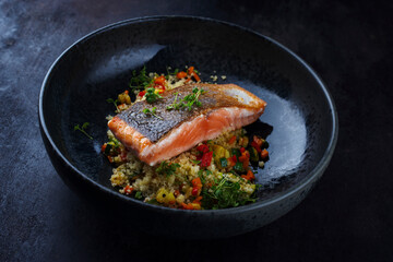 Traditional Mediterranean salmon fish fillet with vegetable cuscus served as close-up on a design bowl with copy space