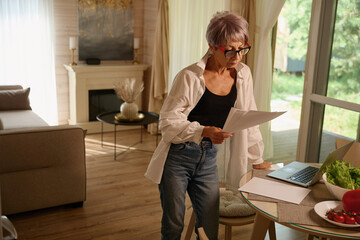 Female in glasses at home in kitchen with work papers