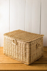 Wicker chest made of natural willow wicker on a wooden background - 702999993