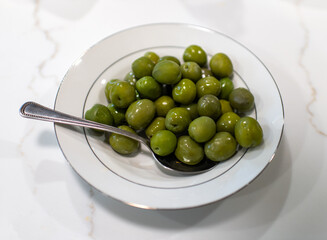green olives in a bowl with a spoon 